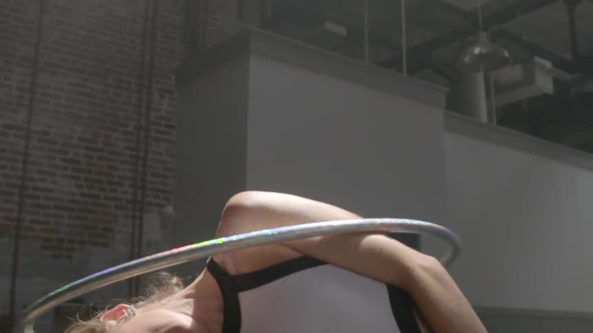 A woman hula hoops with her shoulder