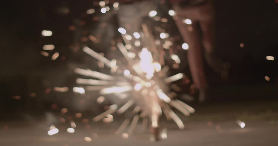 Two people jump over burning fireworks