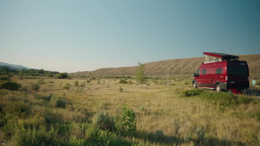 The red van is parked by the hills