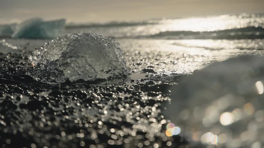 Pieces of ice and icebergs melt along the coast as waves roll in to shore