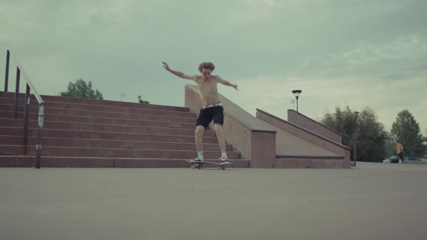 Teenage boy on a skateboard turns as he leaps over stairs and maintains balance on his skateboard