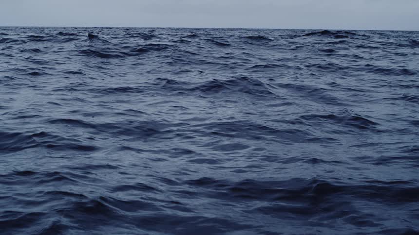 The surface of an ocean with some ripples and dense blue waters