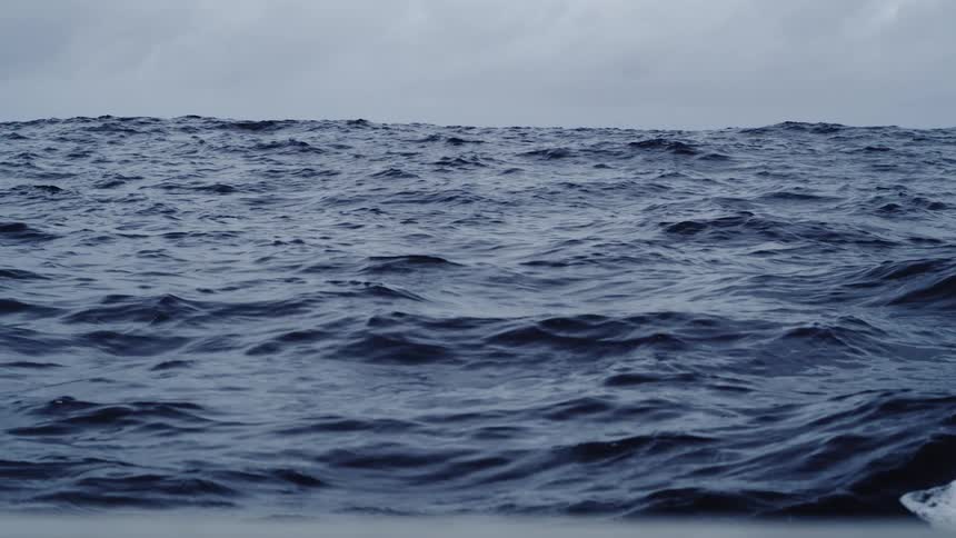 Choppy sea under cloudy sky with gentle waves and obscured horizon