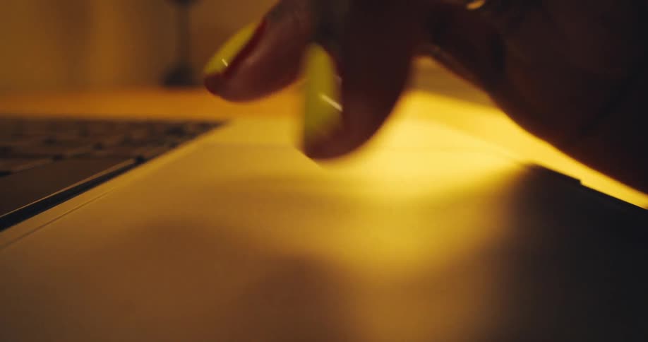 A persons hand with yellow fingernails using a laptop touchpad