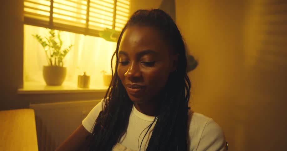 A black woman types on a laptop keyboard while laughing and smiling