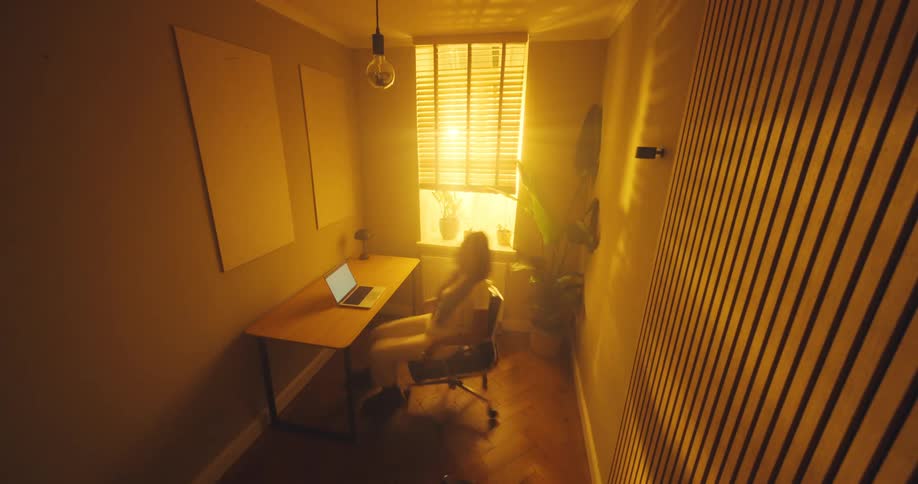 Timelapse of a woman sitting at a table opens her laptop computer and types on the keyboard and moves around