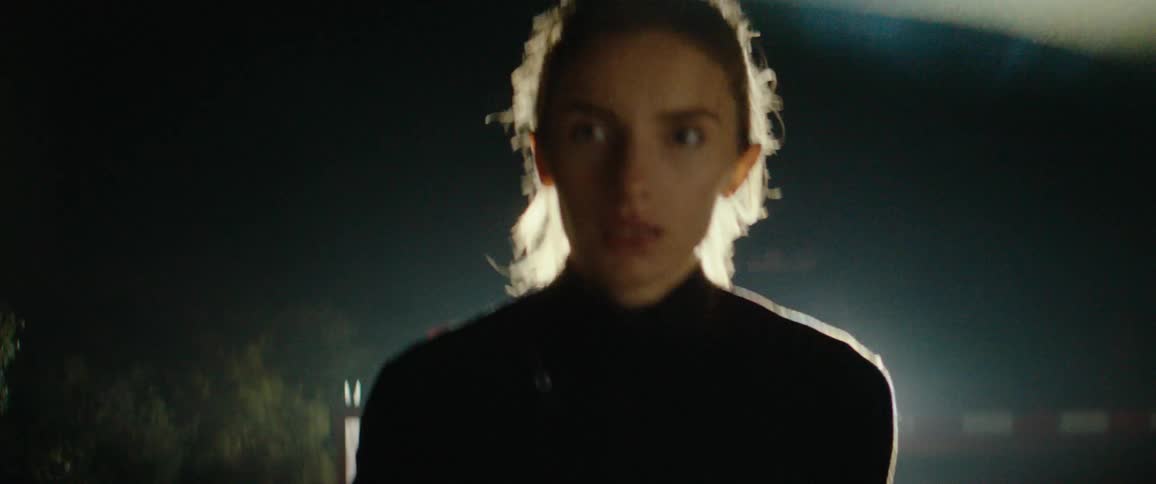 A woman checks her smartwatch while jogging outdoors at night