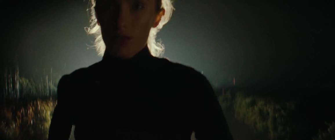 A woman running in the dark under a spotlight