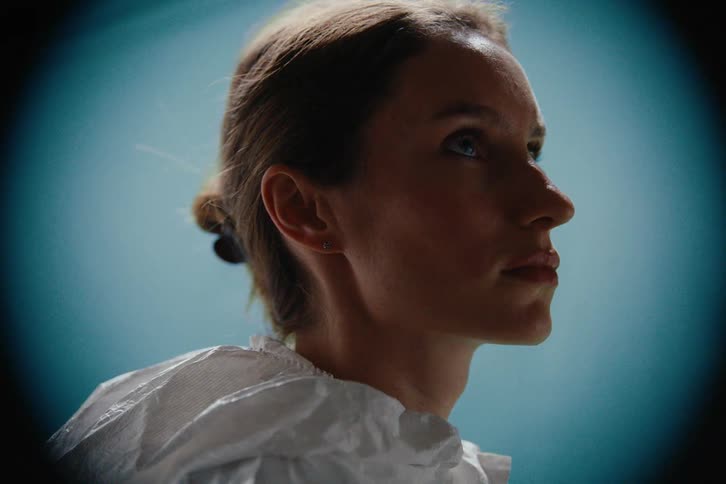 Woman in white protective suit illuminated by a vertical beam of light facial recognition