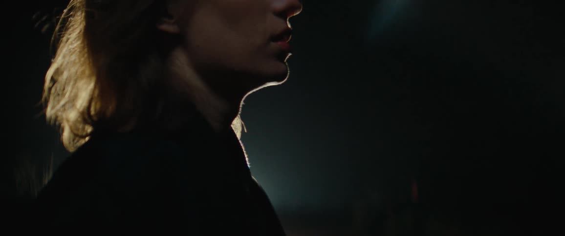 Side silhouette of woman with mediumlength hair backlit in a dark setting