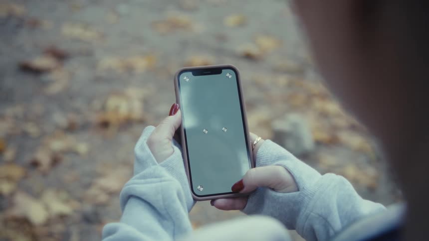 Closeup of hands tapping and playing a game on a smartphone outdoors