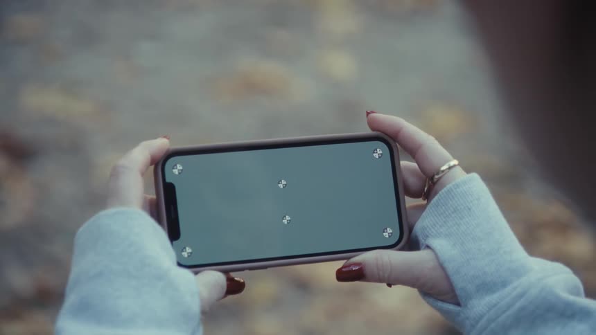A persons hand holding a smartphone with a completely gray screen and some dots at the edges