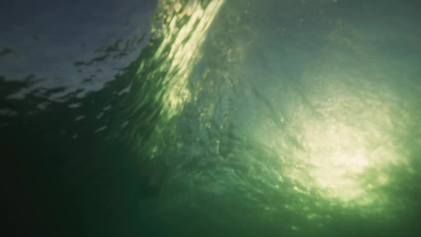 An underwater view of sunlight reflecting on a large wave