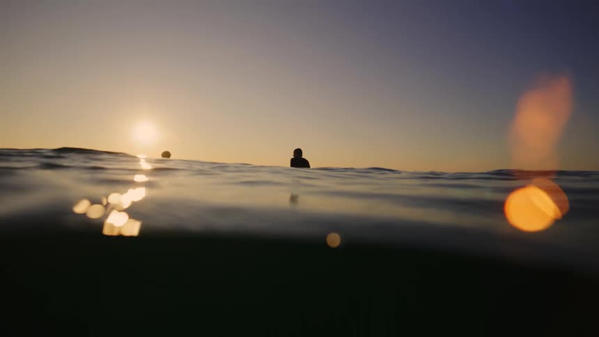 Three people in the sea at sunset
