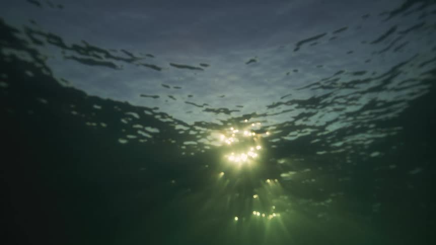 Sun shines through rippled water surface viewed from below