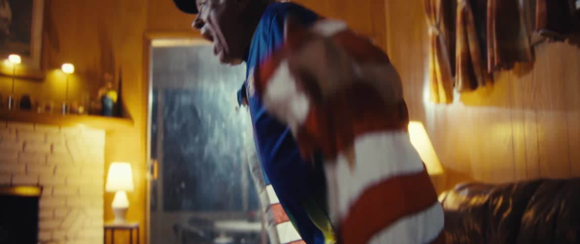 The man stands up and cheers with an american flag around his shoulders