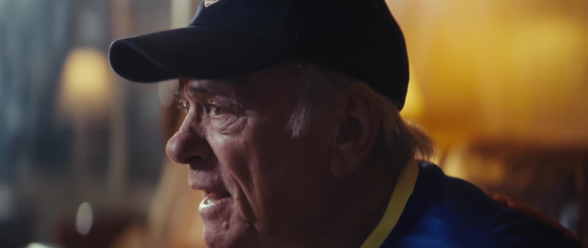 Elderly man sitting down beaming with happiness