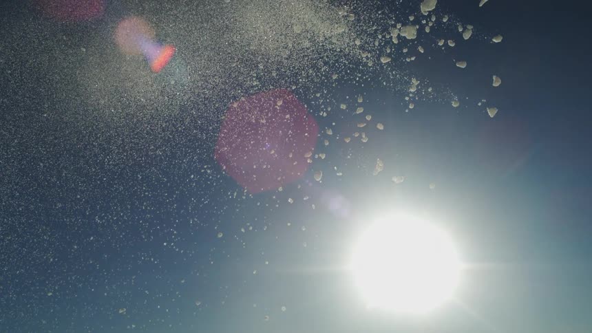 White particles scattered in the air under bright light simulate snowfall
