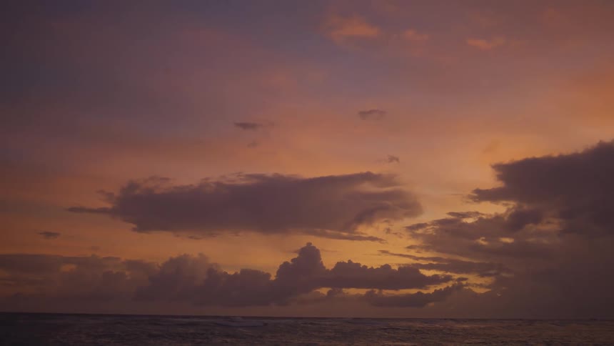 Orangetinted sky stretches over the sea at sunset