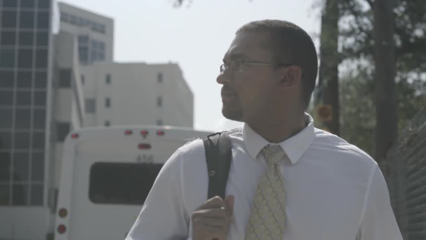 A man is walking in a city with a backpack