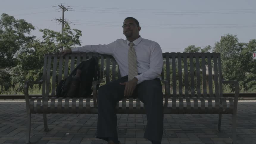 A man sits outside on a bench