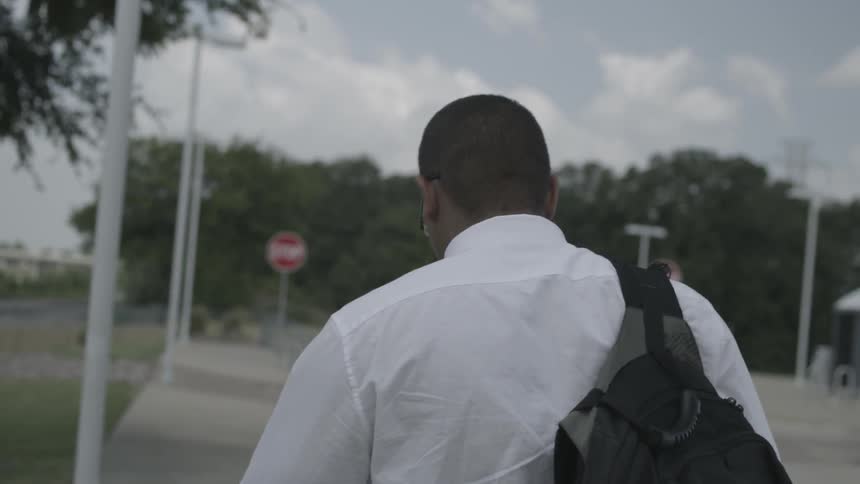 Man wearing a backpack walks down a sidewalk