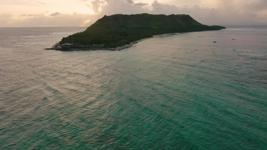 Islet with a plain area and a hill surrounded by the ocean outdoors during day time