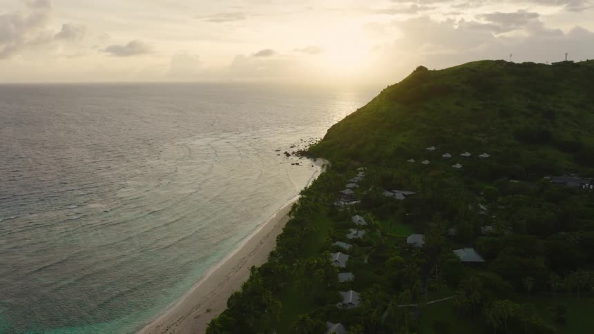 Coastal area with a beach and a cliff surrounded by houses outdoors during dusk or dawn