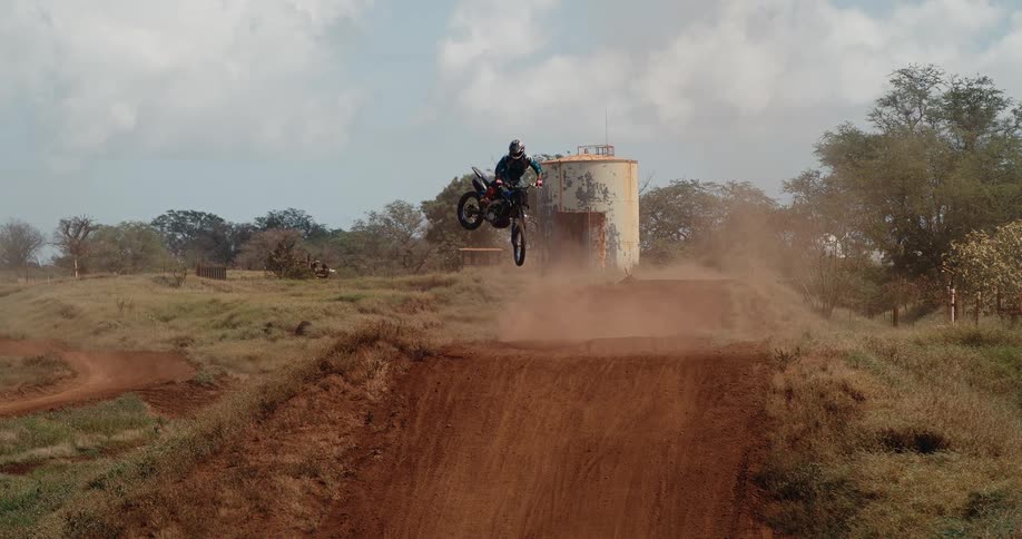 A person on a motorcycle makes a jump on a dirt road