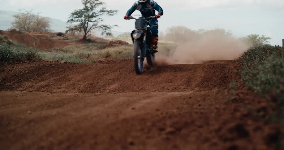 The man speeds on the dirt trail on a dirt bike