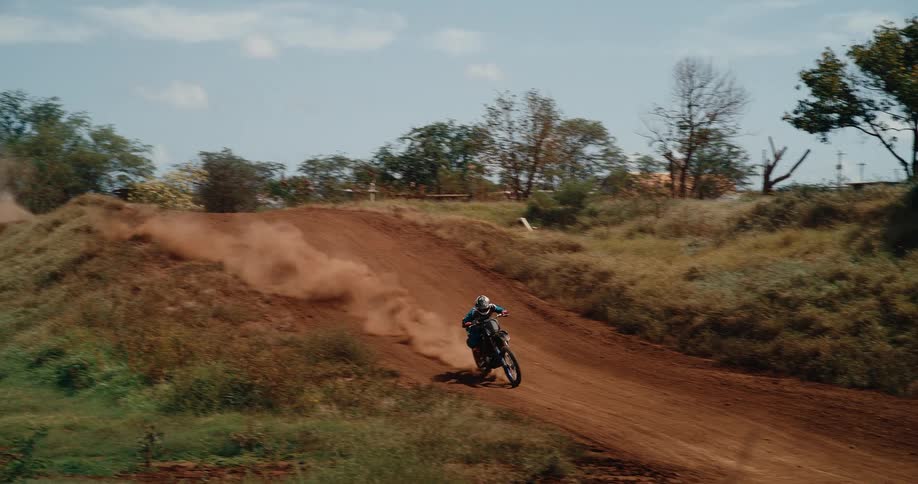 Person riding motorcycle on a dirt road at midday