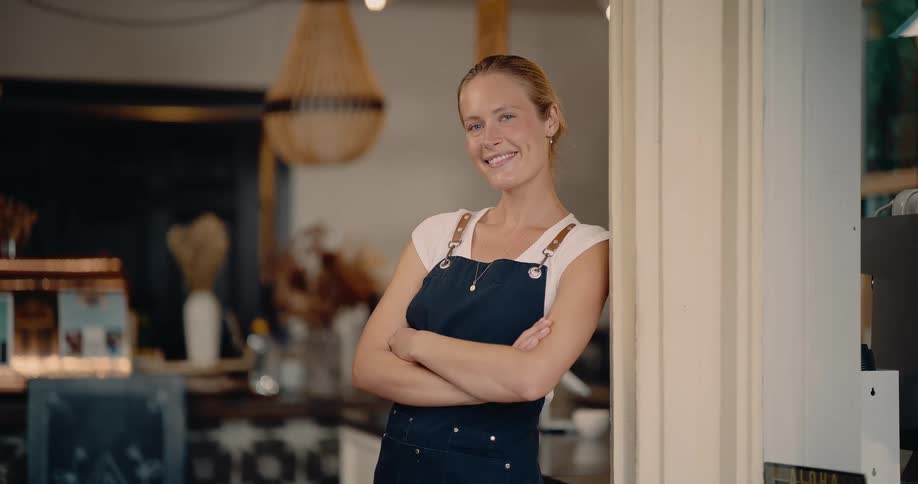 The coffee shop employee smiles by the door