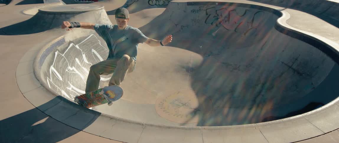 A teenage boy is riding a skateboard doing tricks in a skate park