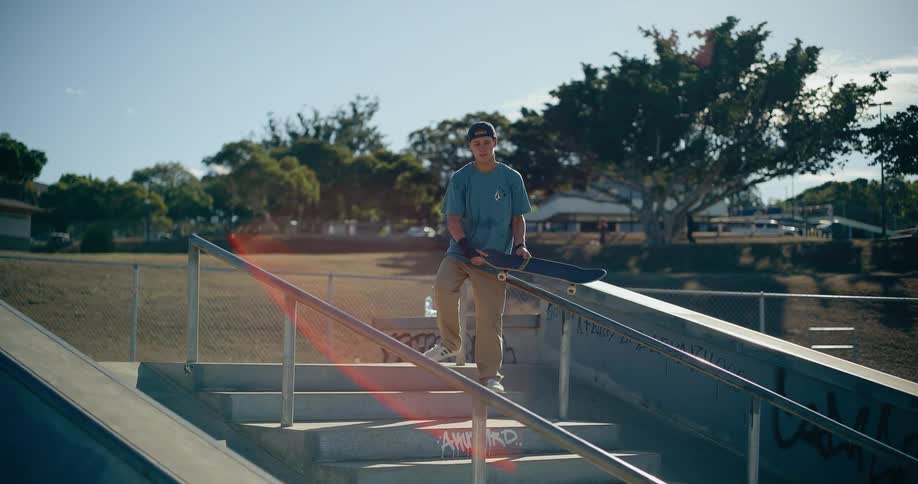 The man carries is skateboards on the steps of the skate park
