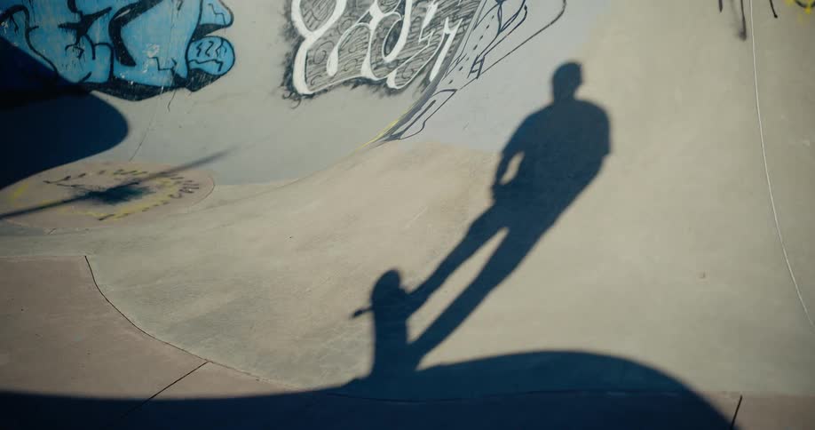 A man rides down a skateboard ramp in a skate park on a sunny day