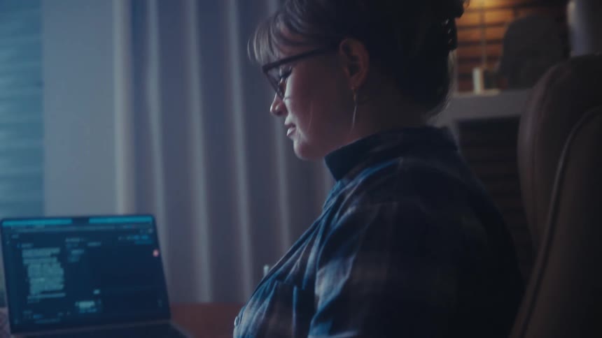 Woman sits at a desk with two computers as she types on a keyboard
