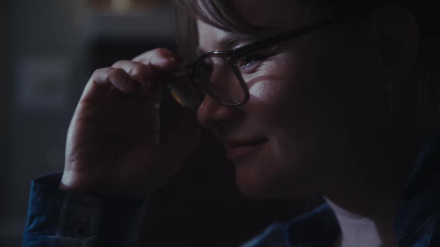 A woman types on her laptop then stops and smiles as she thinks