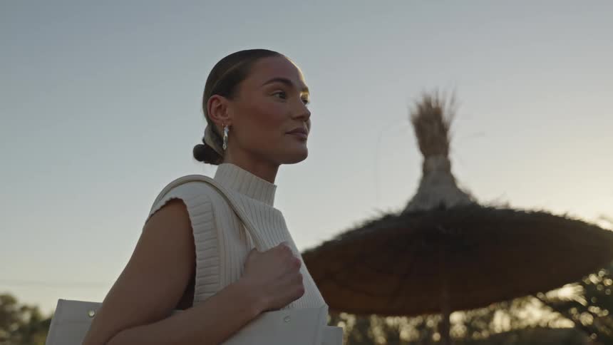 The woman turns her head while standing outside