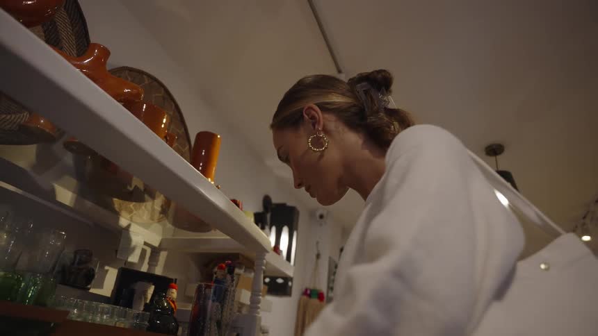 Woman holds a decorative plate while looking at items on a shop shelf