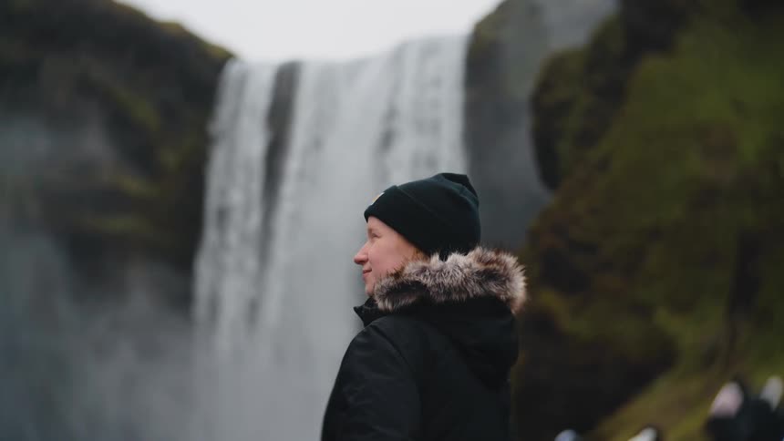 The woman smiles while looking at the waterfall