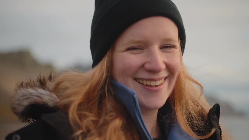 A portrait of a woman standing outdoors smiling
