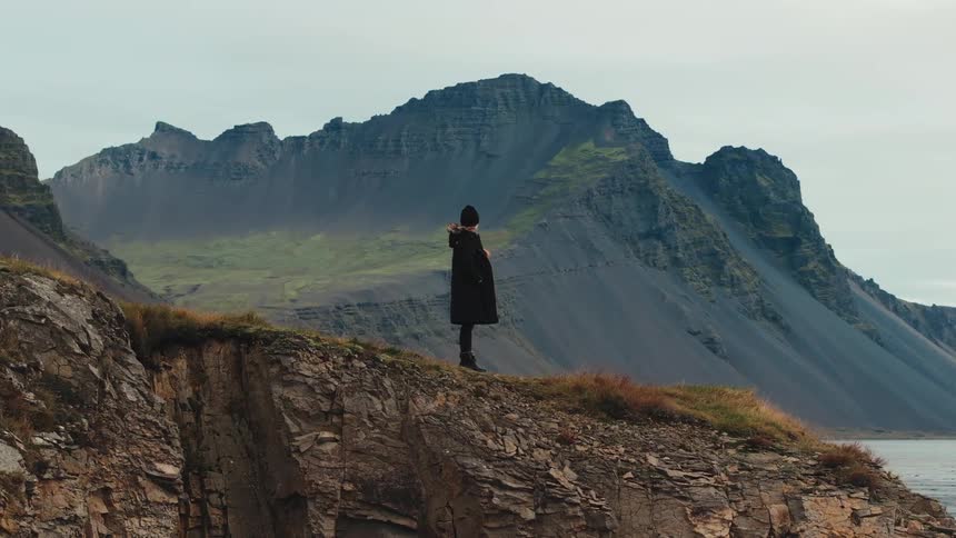 A woman stands on a mountain looking out over a lake