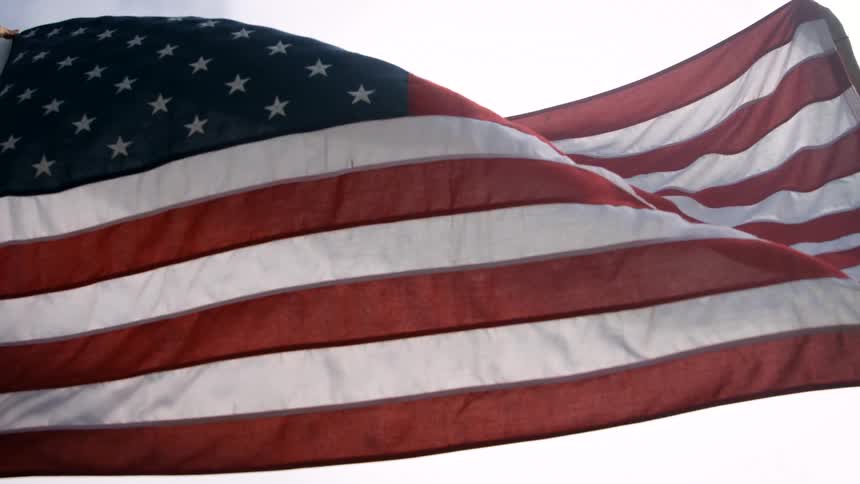 American flag flutters in the breeze against a pale sky