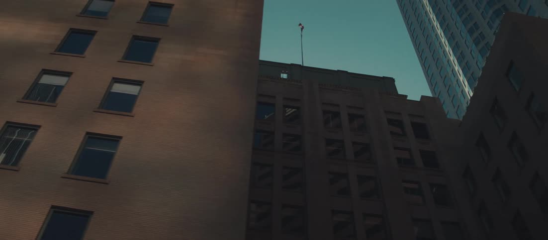 Tall buildings with classic architecture viewed from below against clear blue sky with flag on top