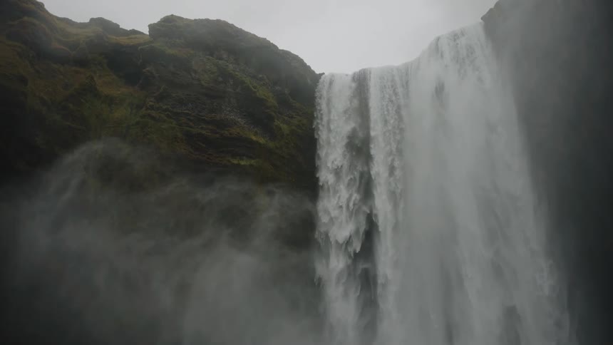 Powerful waterfall plunging down a steep cliff surrounded by moist vegetation
