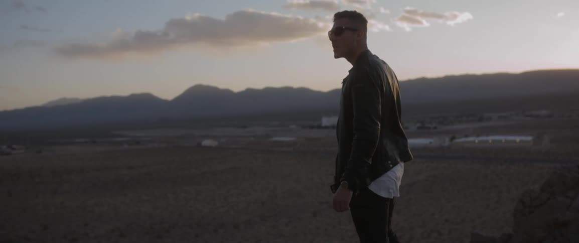 A man stands on a hill by a field