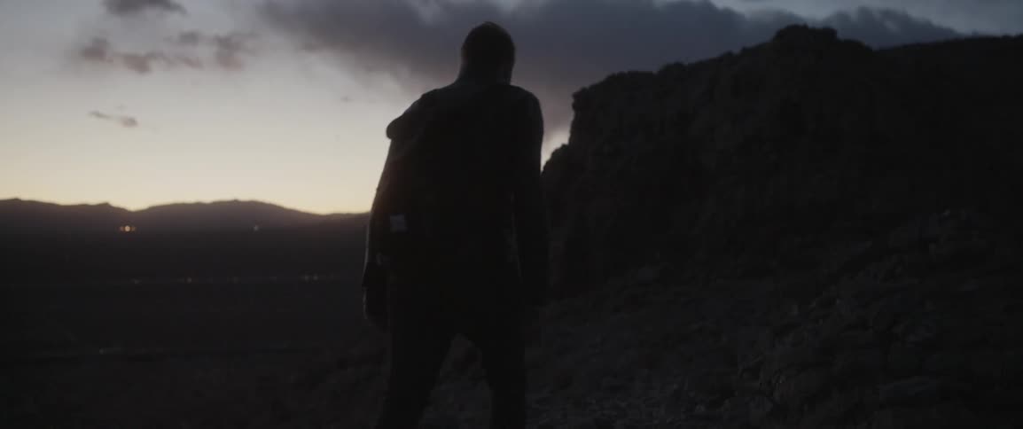 Man wearing backpack walking out in wilderness at dusk