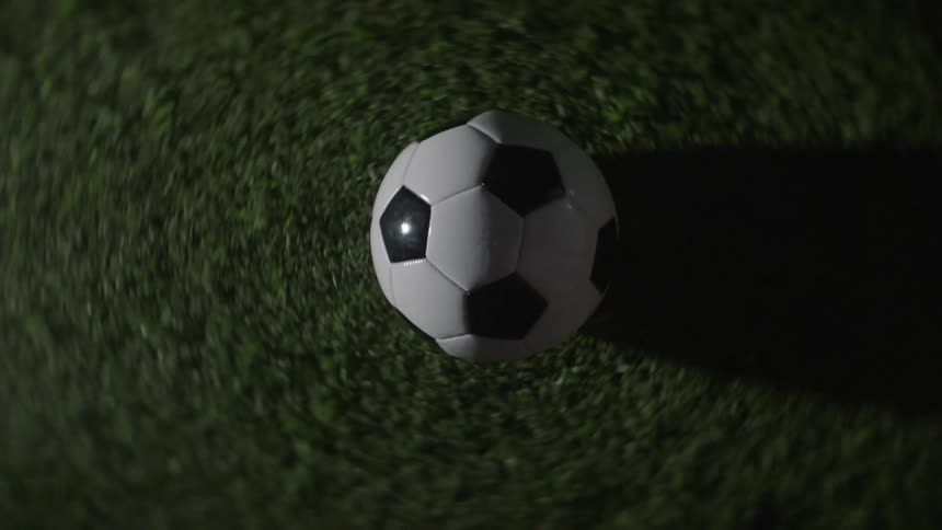 Soccer ball spins on the grass under focused light