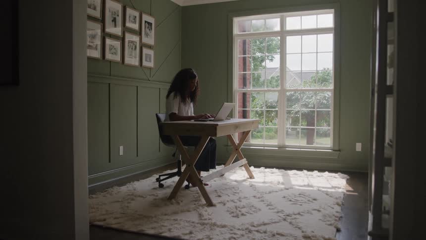 The woman is sitting at her desk typing