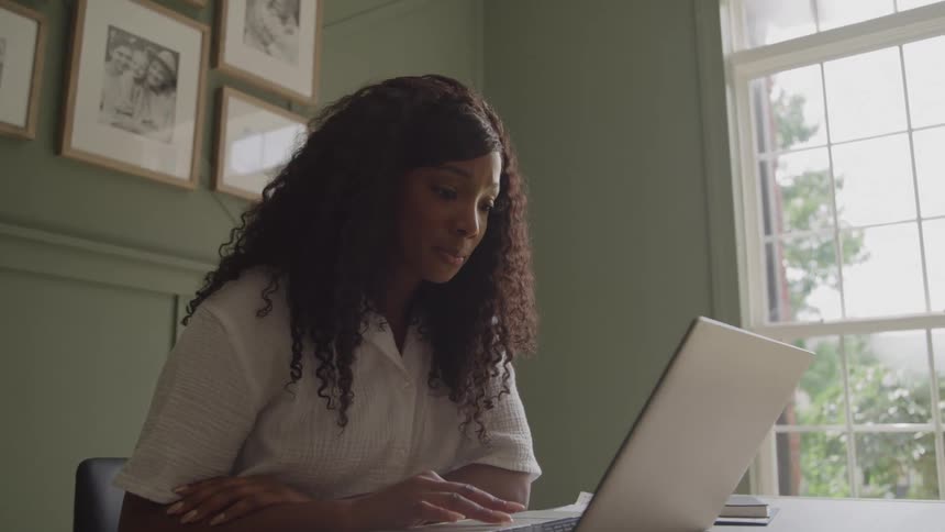 Woman sits at a table working on a laptop computer
